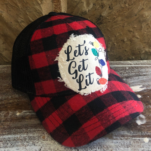 Red and black checkered hat with 'Let's Get Lit' patch on a wooden surface