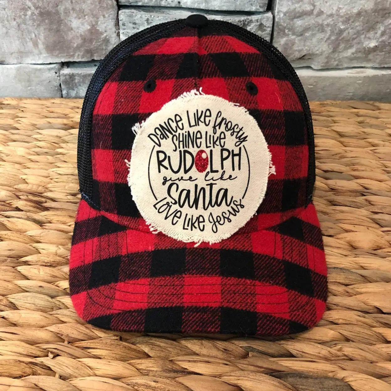Red and black plaid cap with a white circular patch on a woven surface-rudolph