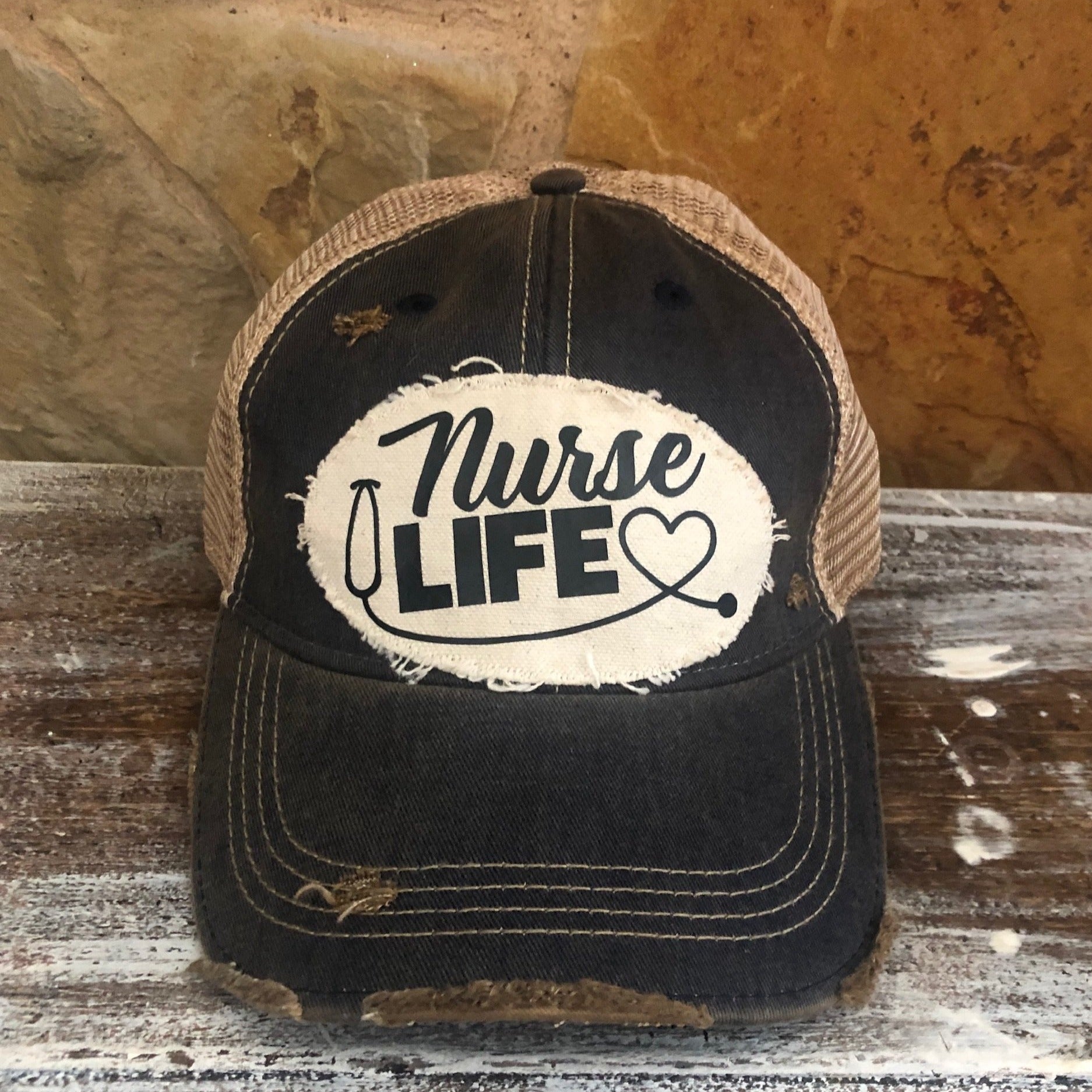 A distressed, vintage black baseball hat with an oversized white 'Nurse Life' logo and a heart symbol