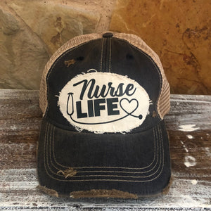 A distressed, vintage black baseball hat with an oversized white 'Nurse Life' logo and a heart symbol