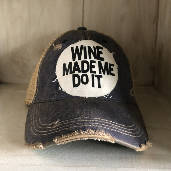 A distressed blue baseball cap with a white 'WINE MADE ME DO IT' text on the front.