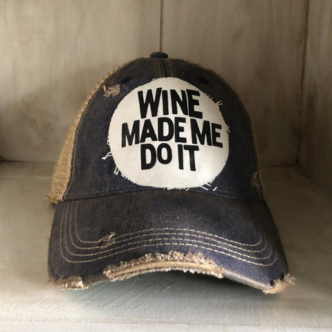 A distressed blue baseball cap with a white 'WINE MADE ME DO IT' text on the front.
