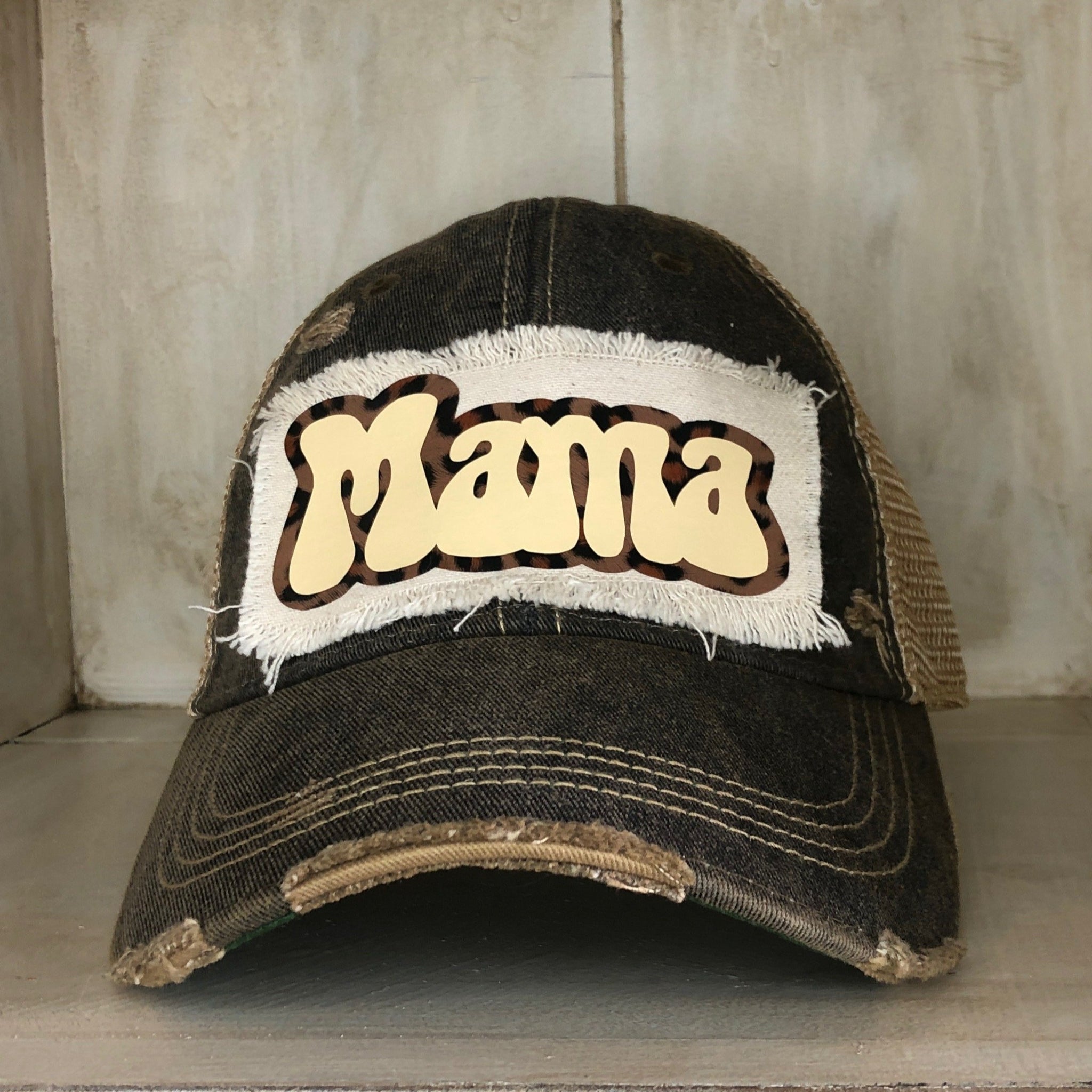 A distressed, vintage black baseball hat with an oversized white 'Mama' logo on the front.