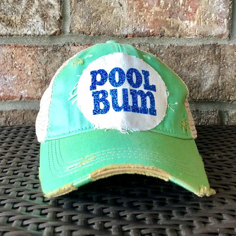 A green distressed baseball cap with an oversized 'POOL BUM' text logo on the front.