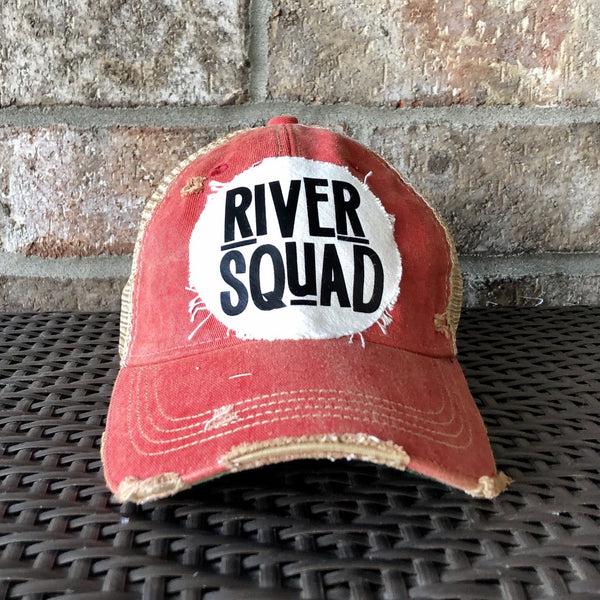 A red distressed baseball cap with an oversized white 'River Squad' logo on the front.