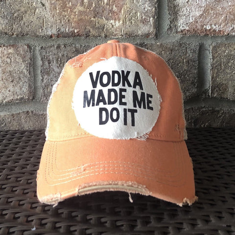 A vintage orange baseball cap with 'VODKA MADE ME DO IT' text on the front.